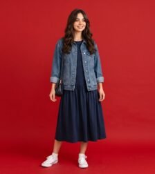 Woman wearing a drop waist dress with white trainers and a denim jacket